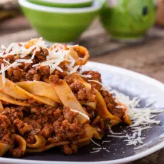 Pappardelle z bogatym sosem bolognese, idealne pytanie: jakie mięso do spaghetti? Posypane parmezanem.