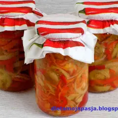 Słoiki z pyszną sałatką z zielonych pomidorów, ozdobione serwetkami z papryczkami chili.