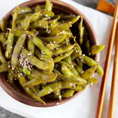 Miseczka pełna zielonych strączków edamame, posypanych sezamem. Idealna przekąska, która wyjaśnia, edamame co to jest.