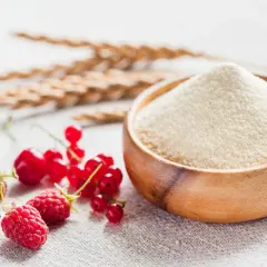 Miseczka z semoliną, obok świeże owoce: truskawka, malina, porzeczka. To właśnie semolina co to za produkt, idealny do deserów i dań.