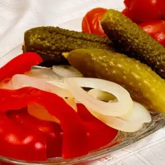 Pikantne ogórki po kaszubsku z papryką i cebulą na talerzu.