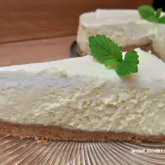 Pyszny sernik na spodzie z herbatników, udekorowany listkiem mięty. Idealny na deser.