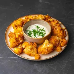 Chrupiący kalafior z airfryer, podany z kremowym sosem czosnkowym i posypany świeżą natką pietruszki. Idealna przekąska!
