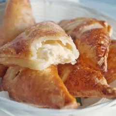 Chrupiące ciasto francuskie z serem, posypane cukrem, w białym koszyku. Idealne na przekąskę.
