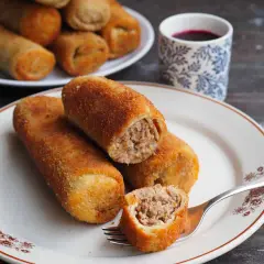 Chrupiące krokiety z mięsem z rosołu, idealne na obiad. Na talerzu kilka sztuk, jeden przekrojony widelcem, ukazując soczyste nadzienie.