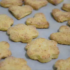 Szybkie ciasteczka twarogowe w kształcie kwiatków i serduszek, posypane cukrem, gotowe do pieczenia.