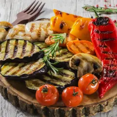 Pyszne przystawki do grilla: grillowany bakłażan, papryka, pieczarki, pomidorki i cebula, ozdobione rozmarynem.