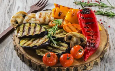 Pyszne przystawki do grilla: grillowany bakłażan, papryka, pieczarki, pomidorki i cebula, ozdobione rozmarynem.