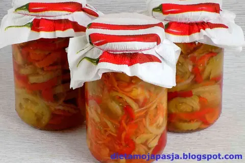 Słoiki z pyszną sałatką z zielonych pomidorów, ozdobione serwetkami z papryczkami chili.