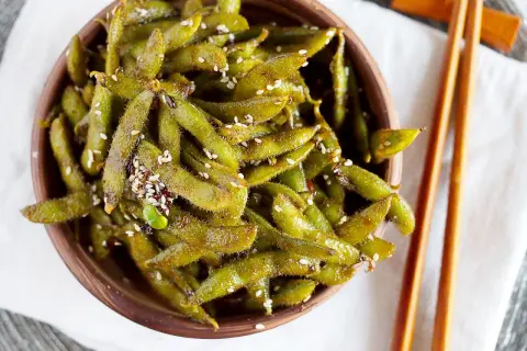 Miseczka pełna zielonych strączków edamame, posypanych sezamem. Idealna przekąska, która wyjaśnia, edamame co to jest.