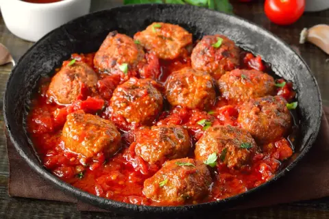 Pyszne mielone w sosie pomidorowym, podane w czarnej patelni. Aromatyczne, soczyste klopsiki w bogatym sosie.