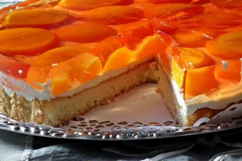 Sernik z brzoskwiniami w galaretce, idealny deser, który pokazuje, ile tężeje galaretka.