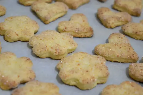 Szybkie ciasteczka twarogowe w kształcie kwiatków i serduszek, posypane cukrem, gotowe do pieczenia.
