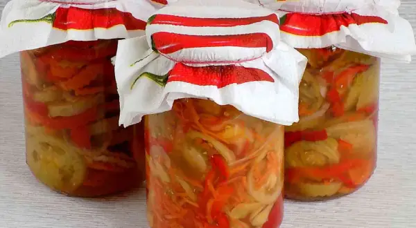 Słoiki z pyszną sałatką z zielonych pomidorów, ozdobione serwetkami z papryczkami chili.
