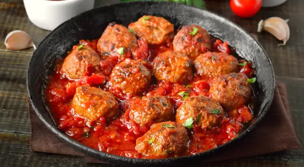 Pyszne mielone w sosie pomidorowym, podane w czarnej patelni. Aromatyczne, soczyste klopsiki w bogatym sosie.