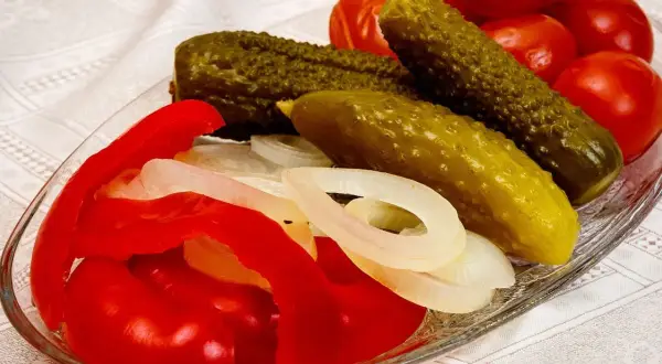 Pikantne ogórki po kaszubsku z papryką i cebulą na talerzu.