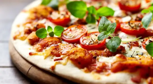 Pyszna pizza bez drożdży z pomidorkami i świeżą bazylią, idealna na szybki obiad.