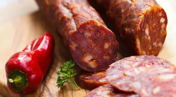 Chorizo co to? Pikantna kiełbasa, czerwona papryka i natka pietruszki na desce.