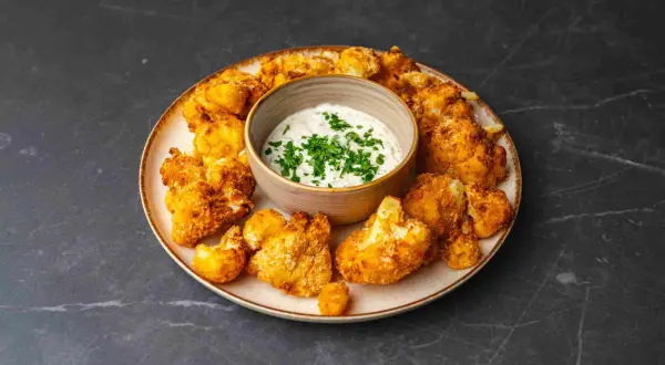 Chrupiący kalafior z airfryer, podany z kremowym sosem czosnkowym i posypany świeżą natką pietruszki. Idealna przekąska!