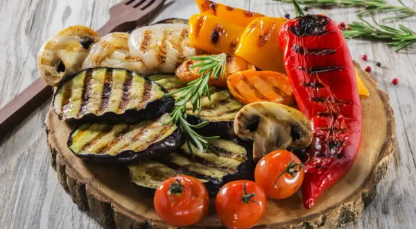 Pyszne przystawki do grilla: grillowany bakłażan, papryka, pieczarki, pomidorki i cebula, ozdobione rozmarynem.