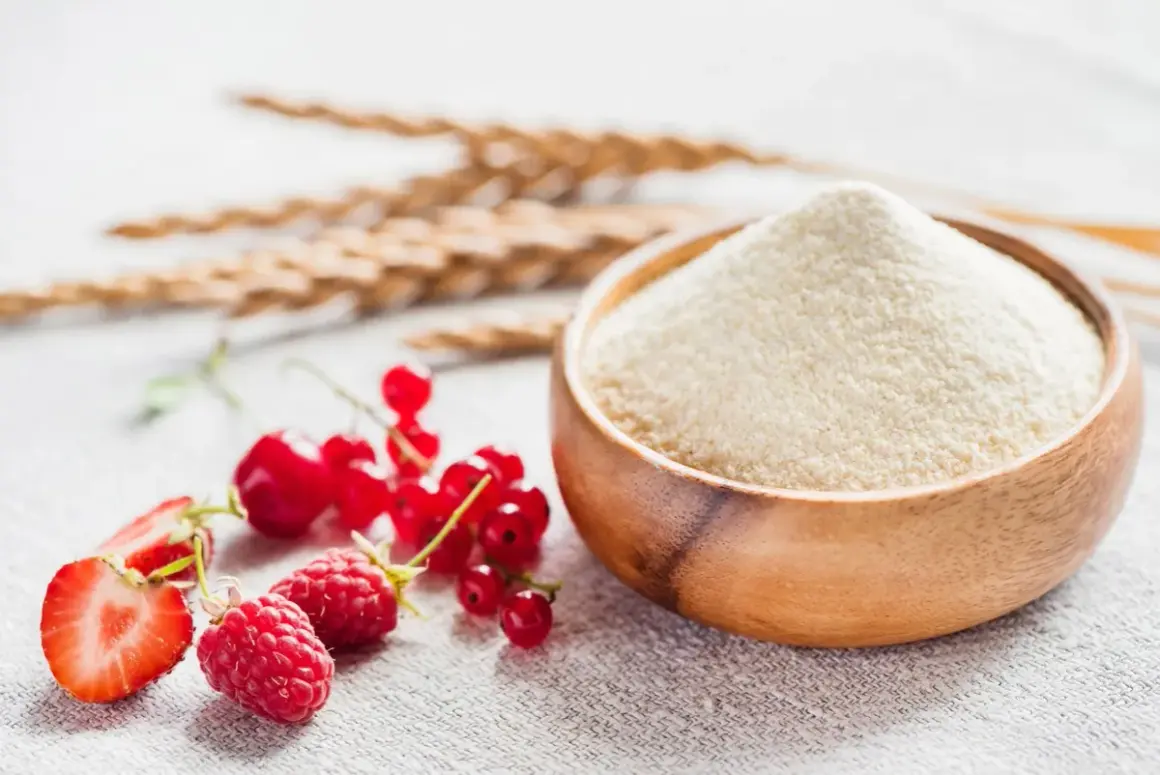 Miseczka z semoliną, obok świeże owoce: truskawka, malina, porzeczka. To właśnie semolina co to za produkt, idealny do deserów i dań.