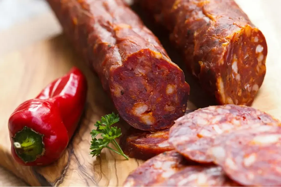 Chorizo co to? Pikantna kiełbasa, czerwona papryka i natka pietruszki na desce.