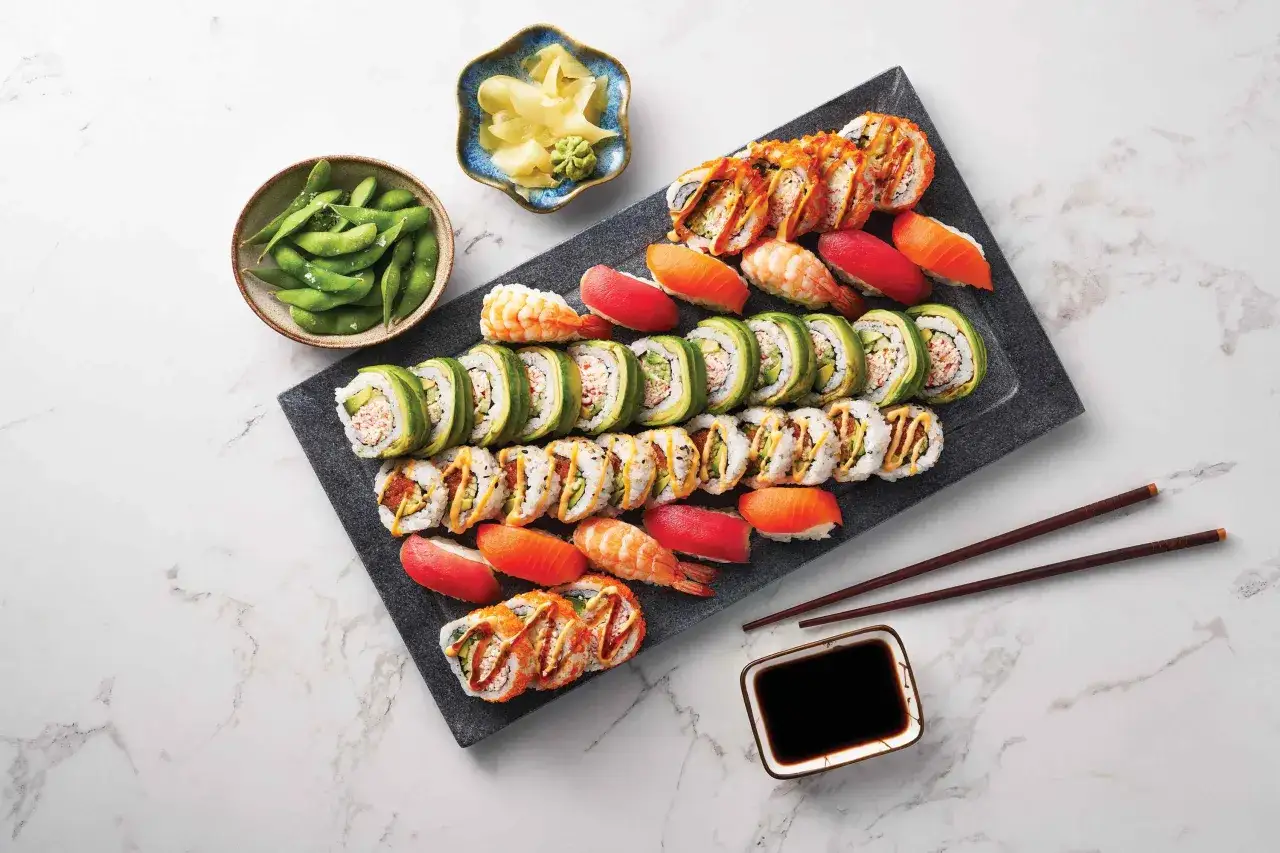 Talerz pełen r&oacute;żnorodnych roladek sushi, nigiri z łososiem i krewetkami, miseczka edamame i marynowanego imbiru. Idealny zestaw, by zacząć ucztę co do sushi.