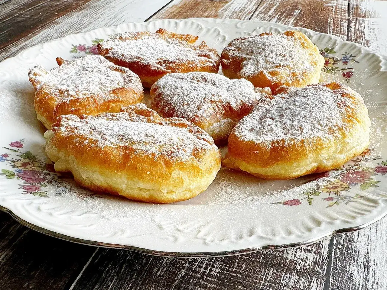 Puszyste racuchy na jogurcie, posypane cukrem pudrem, kuszą swoim złotym kolorem. Idealne na deser!