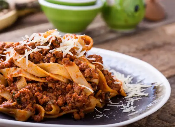 Pappardelle z bogatym sosem bolognese, idealne pytanie: jakie mięso do spaghetti? Posypane parmezanem.