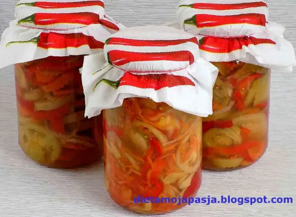 Słoiki z pyszną sałatką z zielonych pomidorów, ozdobione serwetkami z papryczkami chili.