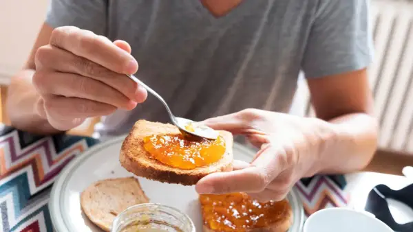 Osoba smaruje łyżeczką tost aromatycznym dżemem z nektarynek. Pyszny początek dnia!