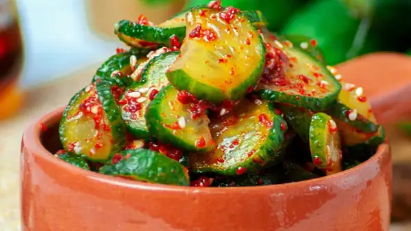 Pikantne ogórki z chili i czosnkiem na zimę, w glinianej miseczce, posypane sezamem.