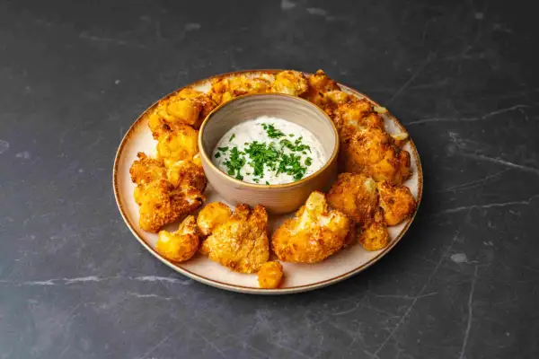 Chrupiący kalafior z airfryer, podany z kremowym sosem czosnkowym i posypany świeżą natką pietruszki. Idealna przekąska!
