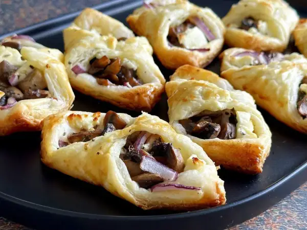 Pyszne przekąski z ciasta francuskiego z pieczarkami, serem i czerwoną cebulą. Idealne na imprezę!