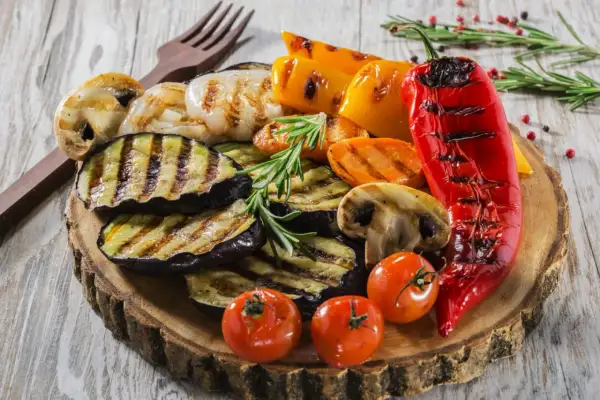 Pyszne przystawki do grilla: grillowany bakłażan, papryka, pieczarki, pomidorki i cebula, ozdobione rozmarynem.